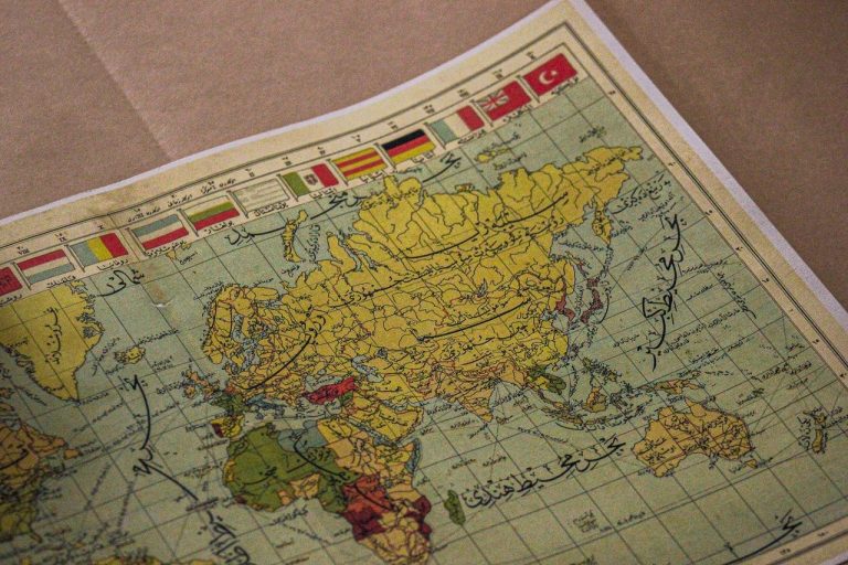 Do eixo diplomático às relações comerciais: os cenários internacionais nos planos de Lula e Flávio Mapa-múndi antigo com continentes, inscrições e bandeiras de diferentes países.