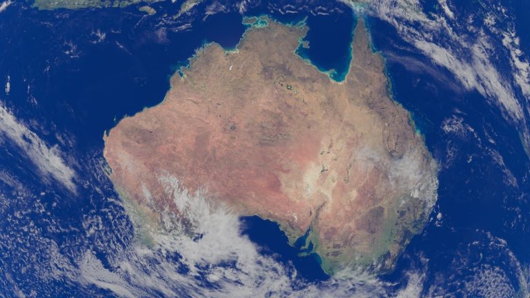 Vista de satélite da Austrália cercada pelo Oceano Pacífico e por áreas de oceano azul.
