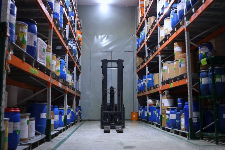 Armazém farmacêutico organizado, com prateleiras de medicamentos e uma empilhadeira.
