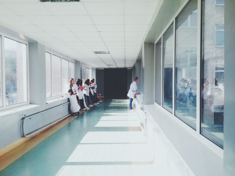 Corredor bem iluminado de hospital com profissionais de saúde usando jalecos brancos