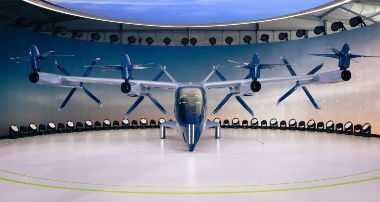 Brasil organiza certificação e espaço aéreo para chegada dos eVTOLs Protótipo de aeronave elétrica com hélices exposto em ambiente interno
